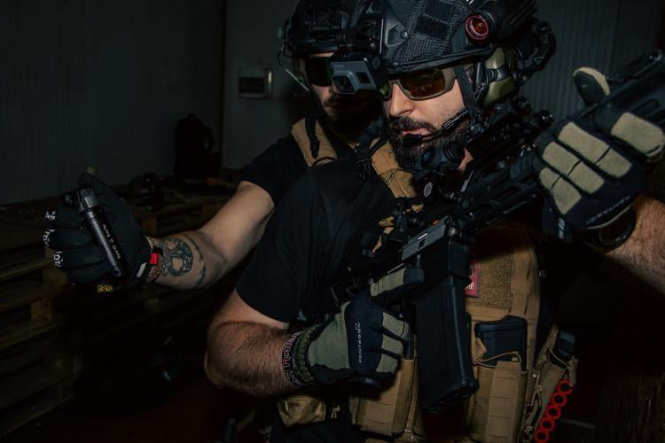 Airsoft operator throwing a reusable impact grenade during CQB room entry