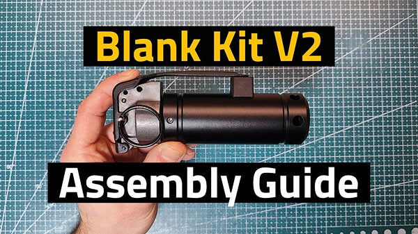 A hand holding a black cylindrical blank kit component against a green cutting mat background, with text overlays reading 'Blank Kit V2' and 'Assembly Guide'.