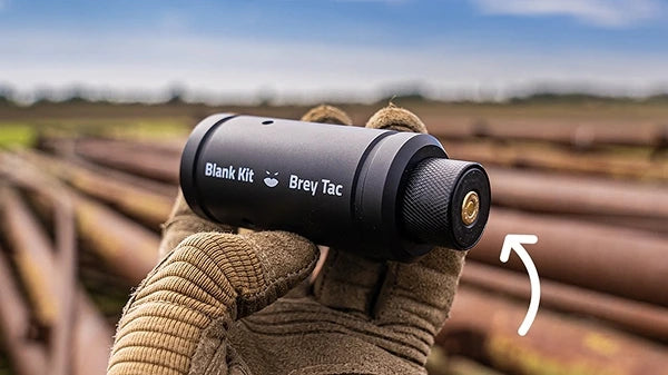 Hand holding Balnk Kit training grenade with tan glove.